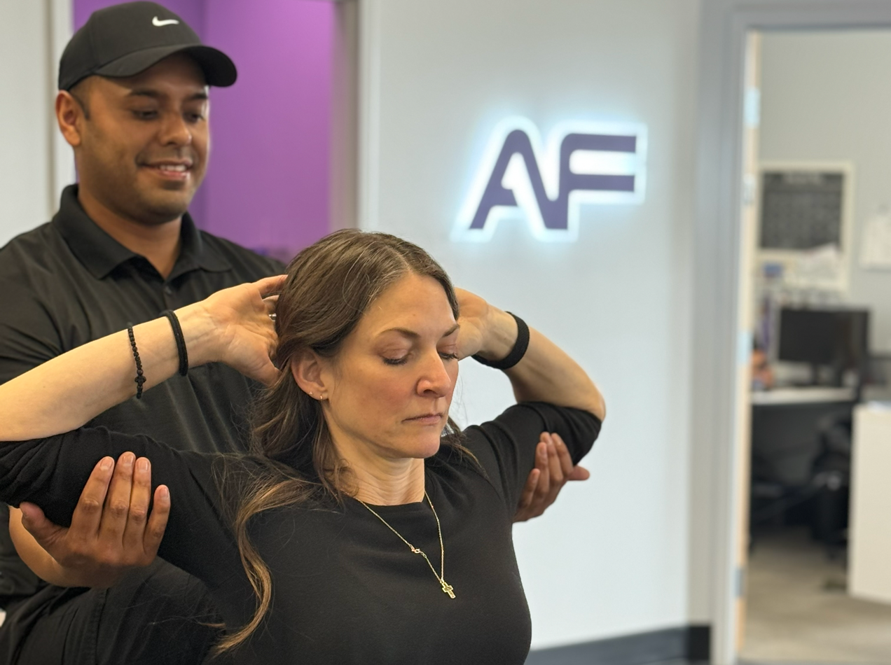 Trainer guiding a woman through a seated upper body assisted stretch during a one-on-one mobility session at Bigstretch Encinitas